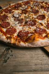 Delicious hot meat pizza with prosciutto and salami on a wooden table. High quality photo