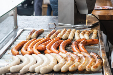 Variety of German sausages on the cooking grate of a hot-dog stall