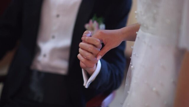 the hands of a beautiful couple of a man and a woman touch at a solemn wedding ceremony