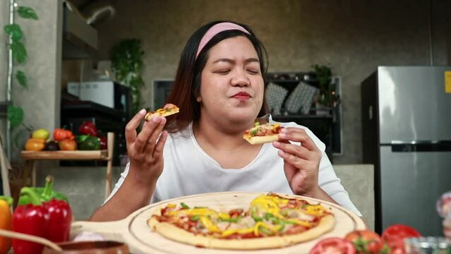 Perfect fat Asian woman sitting and eating delicious Italian pizza with both hands, favorite food, very happy to eat for her.