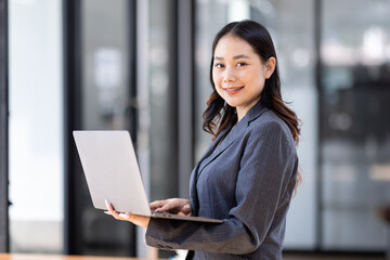 Image of young asian woman, company worker in office, smiling and holding digital tablet, standing over white background blur office
