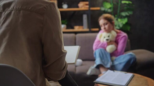 Psychotherapist makes notes while listening to teen girl