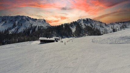 Alpine hut with mountains and orange sunset