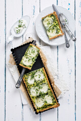 Traditional French tart with buffalo mozzarella and leaf spinach served as top view in a baking form