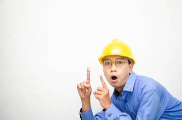 side view of A happy, shocked asian consrtuction worker in blue shirt and yellow safety helmet pointing finger and presenting something ads. 