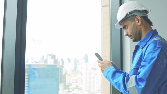 Portrait male architect engineer, construction supervisor talking on smartphone typing messages via application group of workers to perform tasks and command via message for convenience during work.