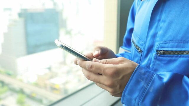 Hands male engineer architect in construction worker uniform talking on smartphone typing message via application worker group to perform tasks and command via message for convenience during work