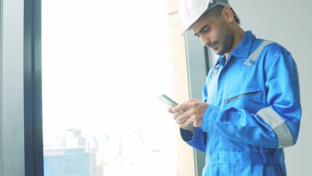 Portrait male architect engineer, construction supervisor talking on smartphone typing messages via application group of workers to perform tasks and command via message for convenience during work.