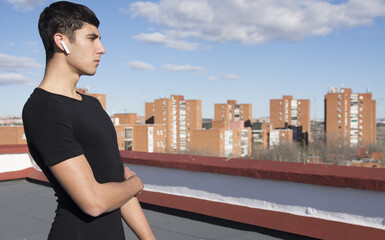 Fototapeta premium Strong sporty sportsman in sport clothes warm up training do stretch exercise on a roof listening to music