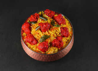 Chicken 65 Biryani served in a bronze bowl black background 