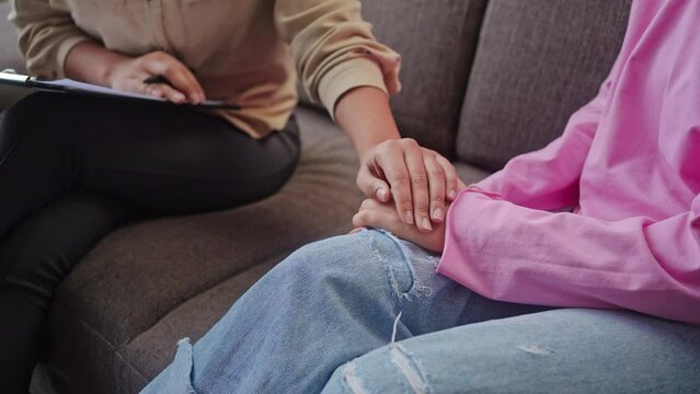 Caring psychologist comforts upset teen girl taking hand