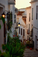 Street of a pretty town with white houses at sunset