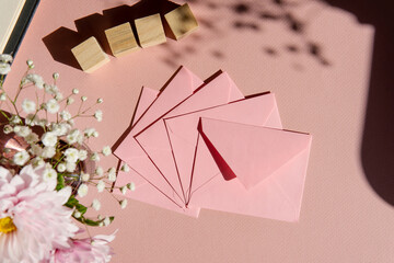pink gift envelope with flowers on a pink background with wooden cubes for an inscription. background for a greeting card.