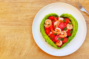 
Heart shaped avocado with roasted shrimps,cherry tomatoes and parleys on plate with wooden...