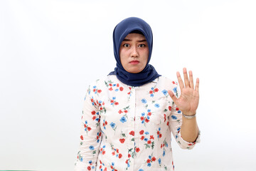 Angry asian muslim woman standing with stop hand gesture. Isolated on white background