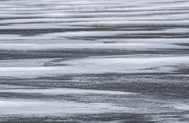 Texture of an icy lake in winter with snow and ice in macro, winter cloudy day