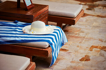 Hat and beach towel on beach wooden chair