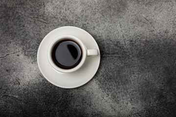 A cup of aromatic coffee on a black marble table. Hot refreshing espresso. Morning drink. Cheerful morning concept.