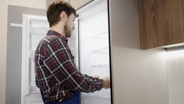 Handyman fixing broken light in a fridge, home appliance maintenance service
