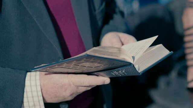 An elderly Jewish man prays standing with a Bible. close up