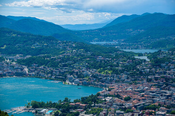 Fototapeta na wymiar Lugano and its lakes, a town in Switzerland is at the base of a mountain in a valley on a sunny summer day