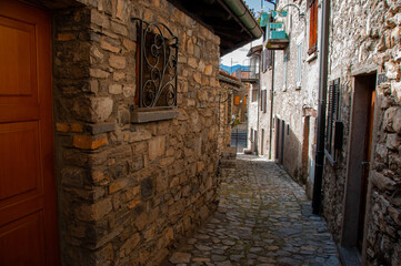 Fototapeta na wymiar A cobblestone alleyway and stone residential houses on a sunny day in the mountains of Lugano Switzerland