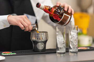 Préparation cocktail barman avec liqueur orange gros plan