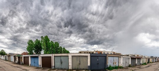 Fototapeta ciemne burzowe chmury i szereg garaży samochodowych obraz