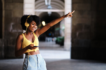 Woman with eyes closed dancing relaxed while listening music with headphones outdoors.