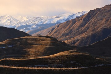 Picturesque mountain landscapes of Dagestan - with ancient terraces and peach trees - and a blue sky with clouds on a sunny winter day.