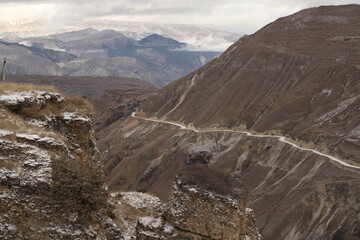 Scenic panorama: foggy mountains, cloudy sky and undulating slopes on a winter day in Dagestan.