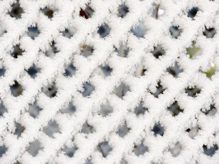 A chain-link fence covered with snow in a sunny winter day