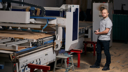 Fototapeta premium A young man stands in a furniture shop near the machine