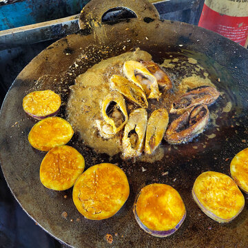 Ilish Fry - Fresh Ilish fish on a big fry pan getting cooked on a hotel at the Mawa Ghat near Padma River in Bangladesh.