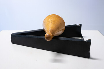 A wooden double cone lies on a slope and rolls upward, seemingly against gravity. The rails running...