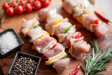 Raw meat skewers with vegetables on wooden background
