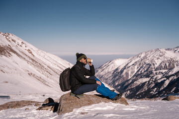 man drinking coffee or tea high in the mountains in winter