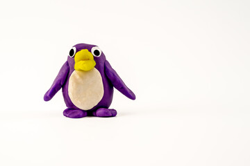 Hand made purple Play dough plasticine penguin with yellow bill isolated on a white background  with copy space