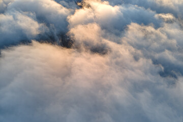 Aerial view from above at high altitude of dense puffy cumulus clouds flying in evening. Amazing...