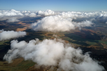 Aerial view from airplane window at high altitude of earth covered with white puffy cumulus clouds