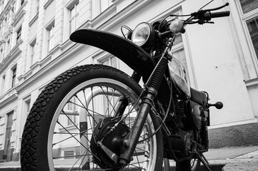 A black and white low angle of a motorcycle in front of a white building in Vienna, Austria