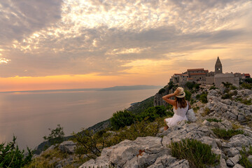 The famoud Lubenice village at sunset over the sea in Cres island Croatia with a woman tourist - obrazy, fototapety, plakaty