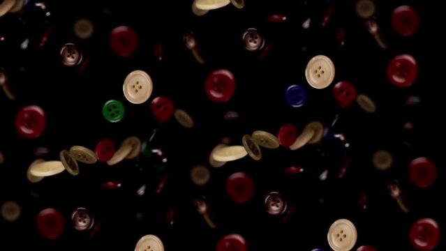 Colored clothes buttons fly in slow motion on a black background