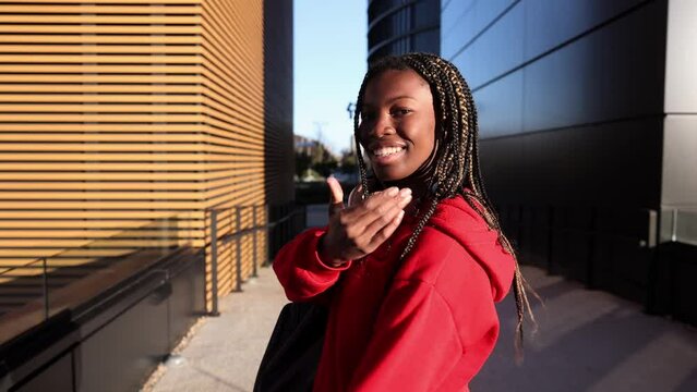 young african woman walking in the traveling city makes follow me gesture