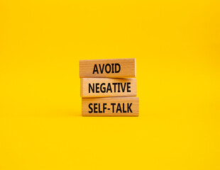 Avoid negative self-talk symbol. Concept words Avoid negative self-talk on wooden blocks. Beautiful yellow background. Business and Avoid negative self-talk concept. Copy space.