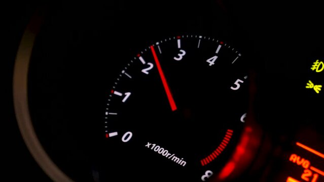 Close up of car speed meter. Footage. Interior of a modern car, dashboard with an engine speed dial and moving red arrow.