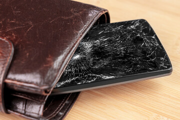 A damaged mobile phone with a shattered touchscreen in a leather wallet