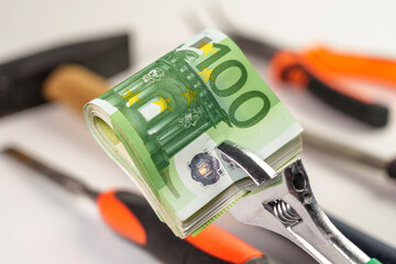 Cash european money clamped in a metal wrench with industrial repair tools