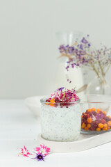 A healthy dessert with yogurt, chia seeds, berries and edible flowers. Close-up on a light background.