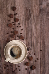 Concept for coffee lovers. A cup of espresso coffee and coffee beans with heart-shaped chocolate truffles on a dark wooden table. Coffee and chocolates on a wooden background. Place for text.